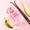My Way Nectar Eau de Parfum by Giorgio Armani surrounded by vanilla beans, citrus slices, and white flowers on a pink background.