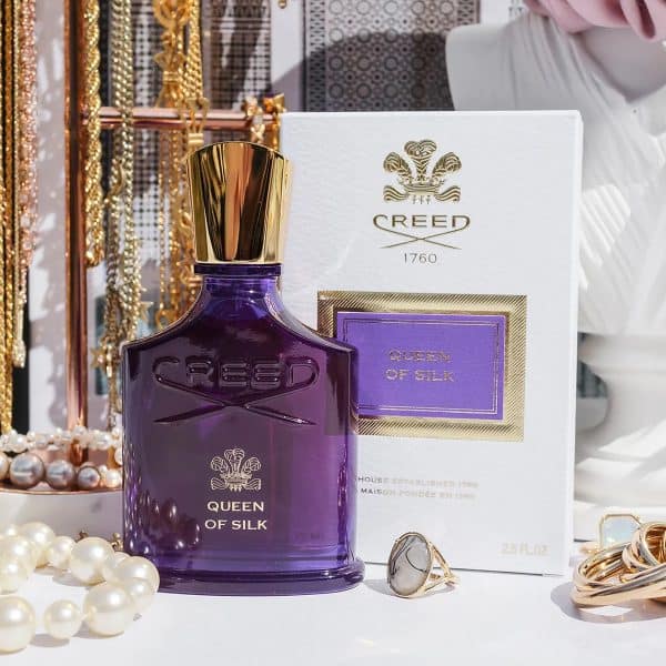 Creed Queen of Silk Eau de Parfum luxury perfume bottle and packaging displayed with pearls, gold jewelry, and elegant vanity decor creating a rich feminine aesthetic.