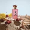 Dolce & Gabbana Q Eau de Parfum fragrance bottle surrounded by fresh cherries and sliced citrus on a rocky desert-inspired backdrop