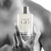 Person holding Acqua Di Gio perfume bottle on bare shoulder.